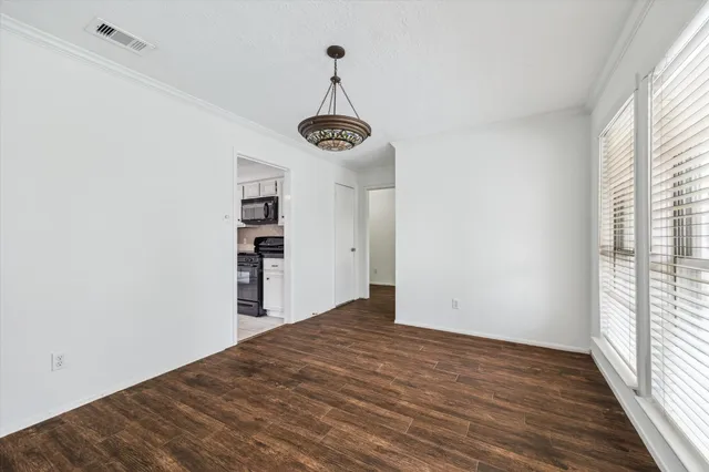 a view of empty room with wooden floor and window