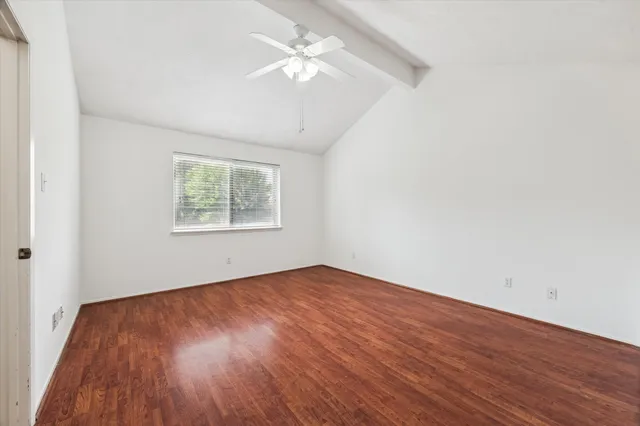 an empty room with wooden floor chandelier fan and windows