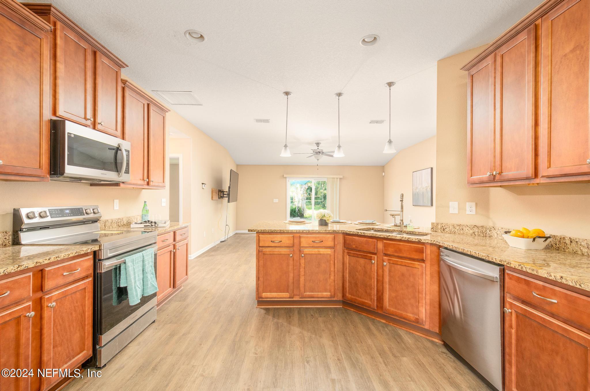 9890 Fraser Road Jacksonville, FL 32246 - Photo 5 of 23 a large kitchen with stainless steel appliances granite countertop a stove top oven a sink dishwasher and white cabinets with wooden floor