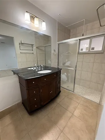 a bathroom with a granite countertop sink a mirror and shower