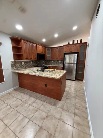 a kitchen with stainless steel appliances granite countertop a stove a sink and a refrigerator