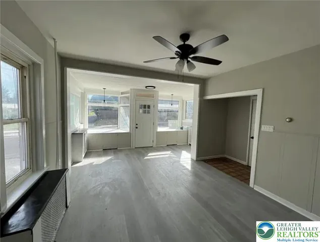 a view of a big room with wooden floor a ceiling fan and windows