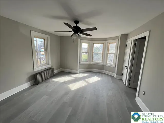 a view of an empty room with a window and wooden floor