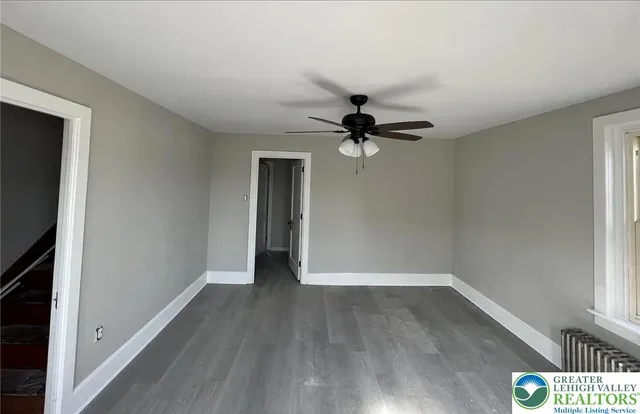 a view of empty room with wooden floor and fan
