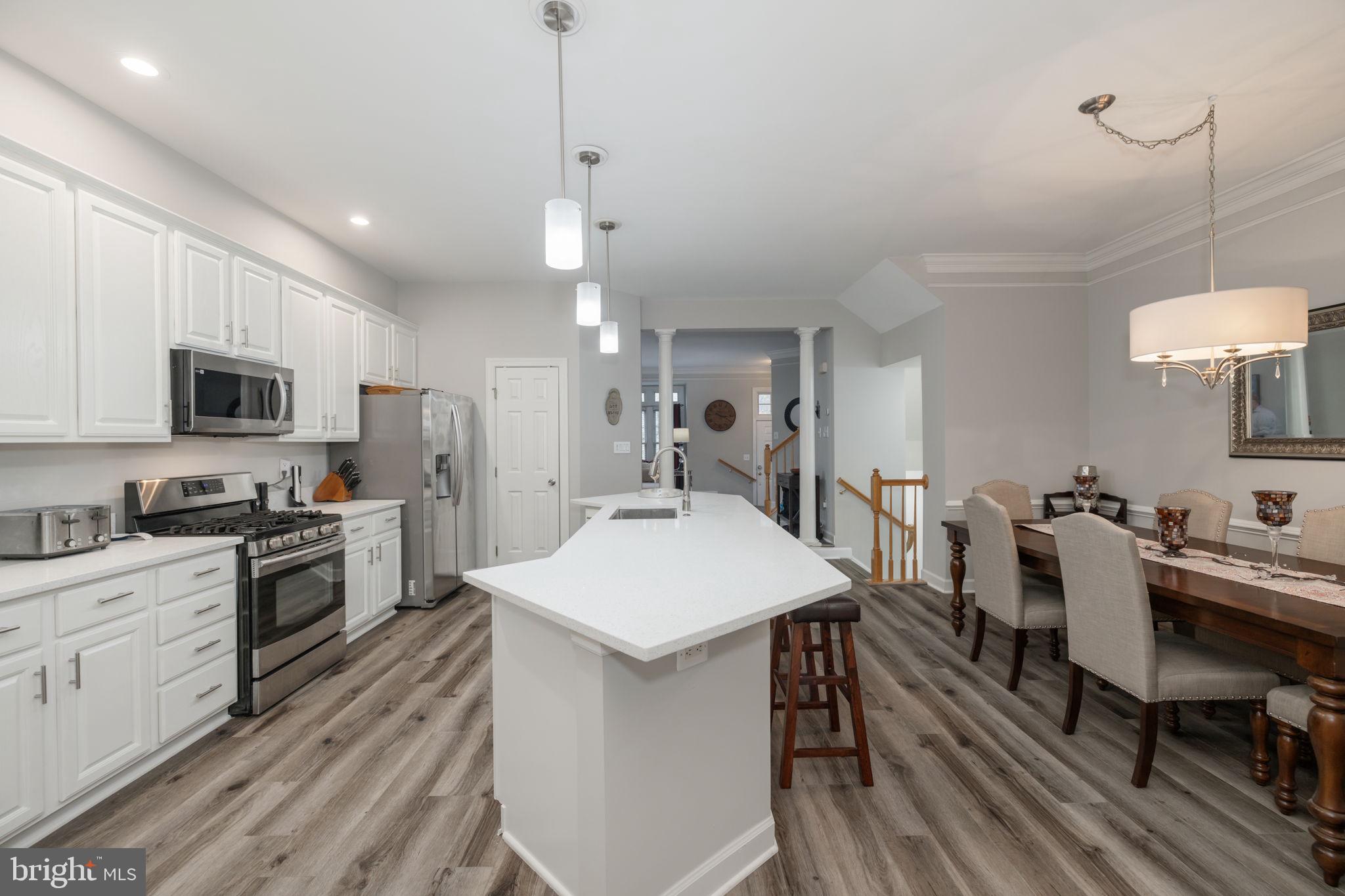 6337 Simmer Circle Springfield, VA 22150 - Photo 13 of 50 a large kitchen with sink a microwave oven a stove and white cabinets with wooden floor