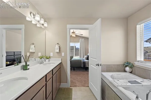 a en suite bathroom with a granite countertop sink a large mirror and a bathtub
