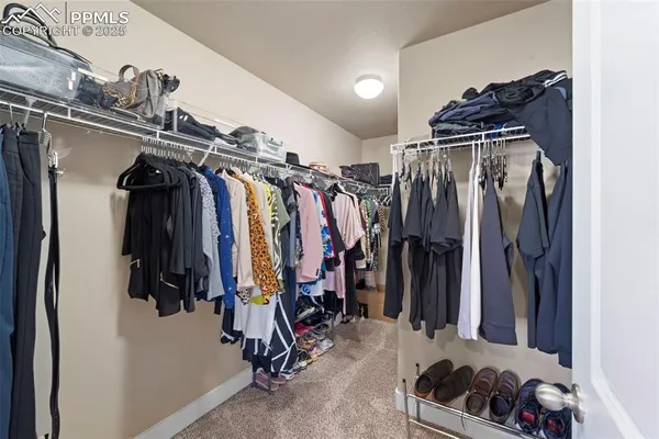 a view of walk in closet with clothes and shoes