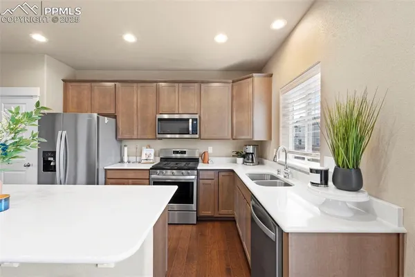 a kitchen with stainless steel appliances a sink a stove a refrigerator cabinets and a counter top space