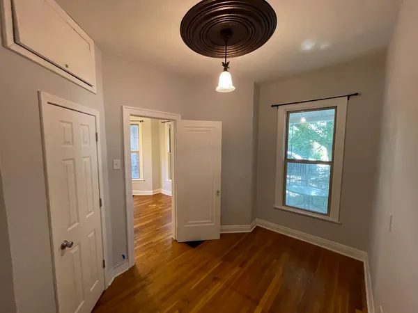 an empty room with wooden floor cabinet and windows