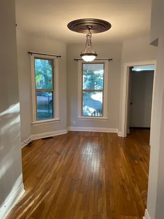 a view of an empty room with wooden floor and chandelier