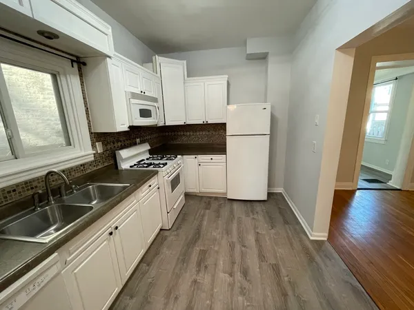 a kitchen with a sink a refrigerator a stove and wooden floor