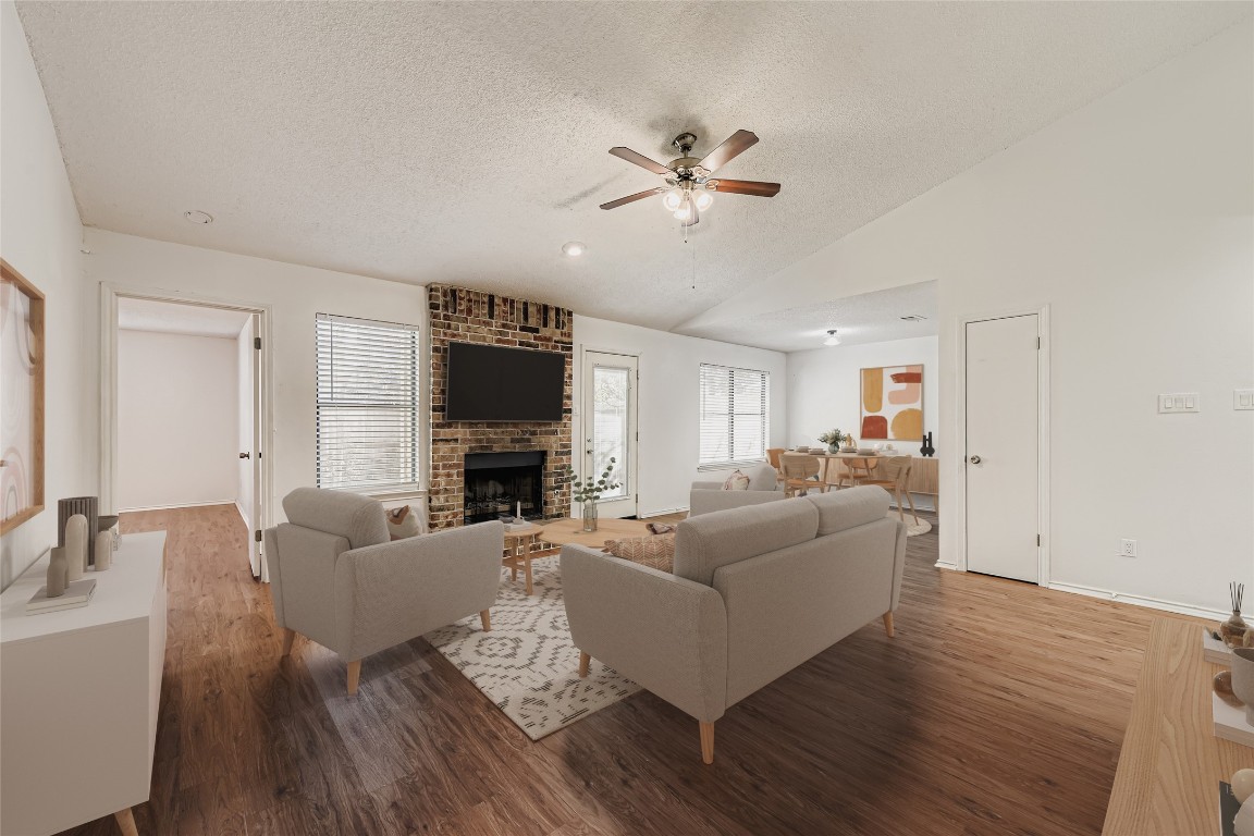 9839 Briar Ridge Drive Austin, TX 78748 - Photo 11 of 28 Living area with a textured ceiling, dark wood finished floors, vaulted ceiling, a ceiling fan, and a fireplace