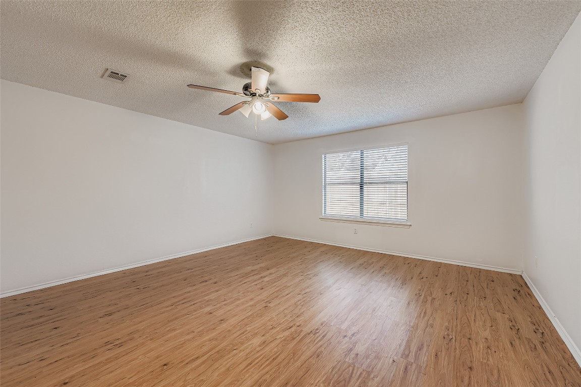 9839 Briar Ridge Drive Austin, TX 78748 - Photo 19 of 28 Empty room with light wood-style floors, a textured ceiling, and a ceiling fan