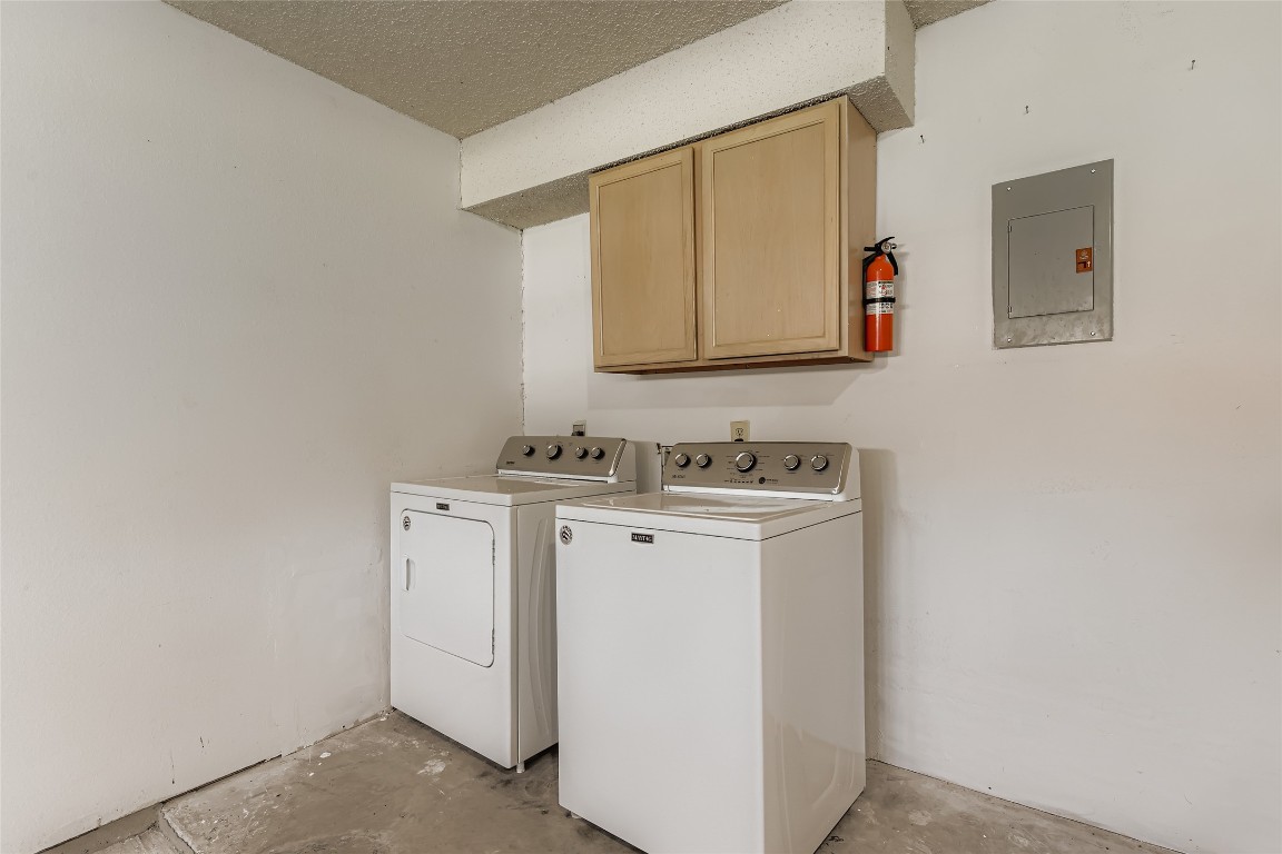 9839 Briar Ridge Drive Austin, TX 78748 - Photo 22 of 28 Washroom featuring unfinished concrete flooring, electric panel, cabinet space, a textured ceiling, and washer and dryer