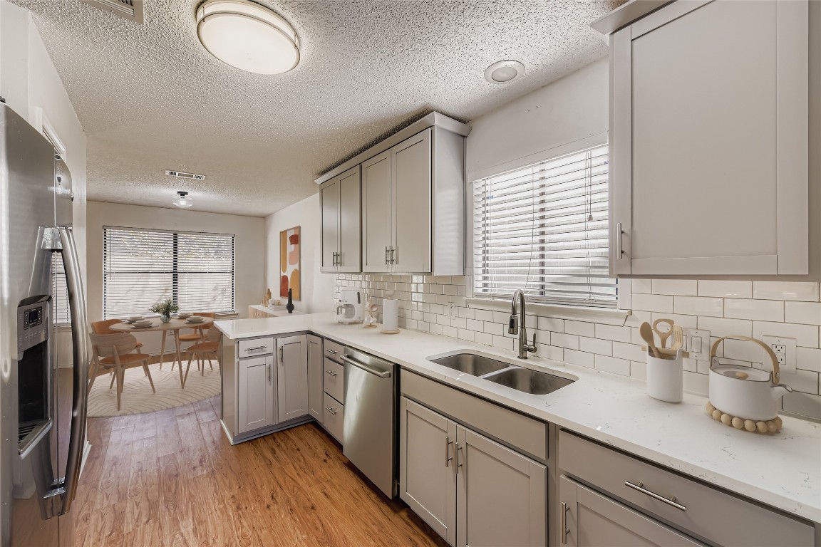 9839 Briar Ridge Drive Austin, TX 78748 - Photo 6 of 28 Kitchen with stainless steel appliances, gray cabinetry, a peninsula, a textured ceiling, and healthy amount of natural light