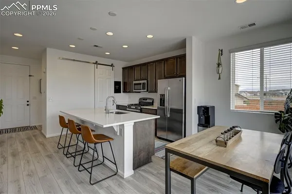 a kitchen with a dining table cabinets appliances and wooden floor