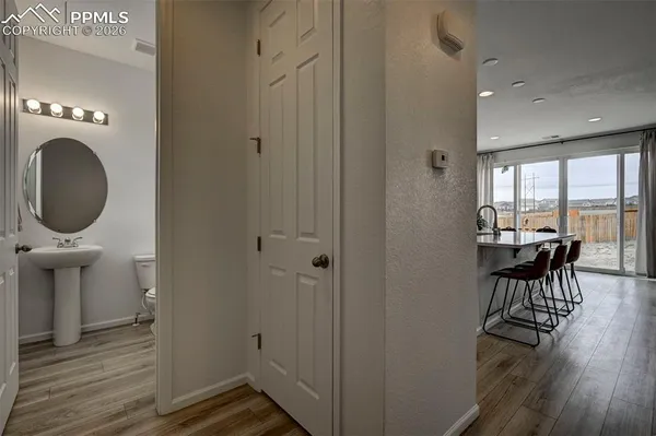 a view of a hallway with wooden floor and a bathroom sink