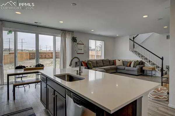 a living room with stainless steel appliances furniture a large window and a sink