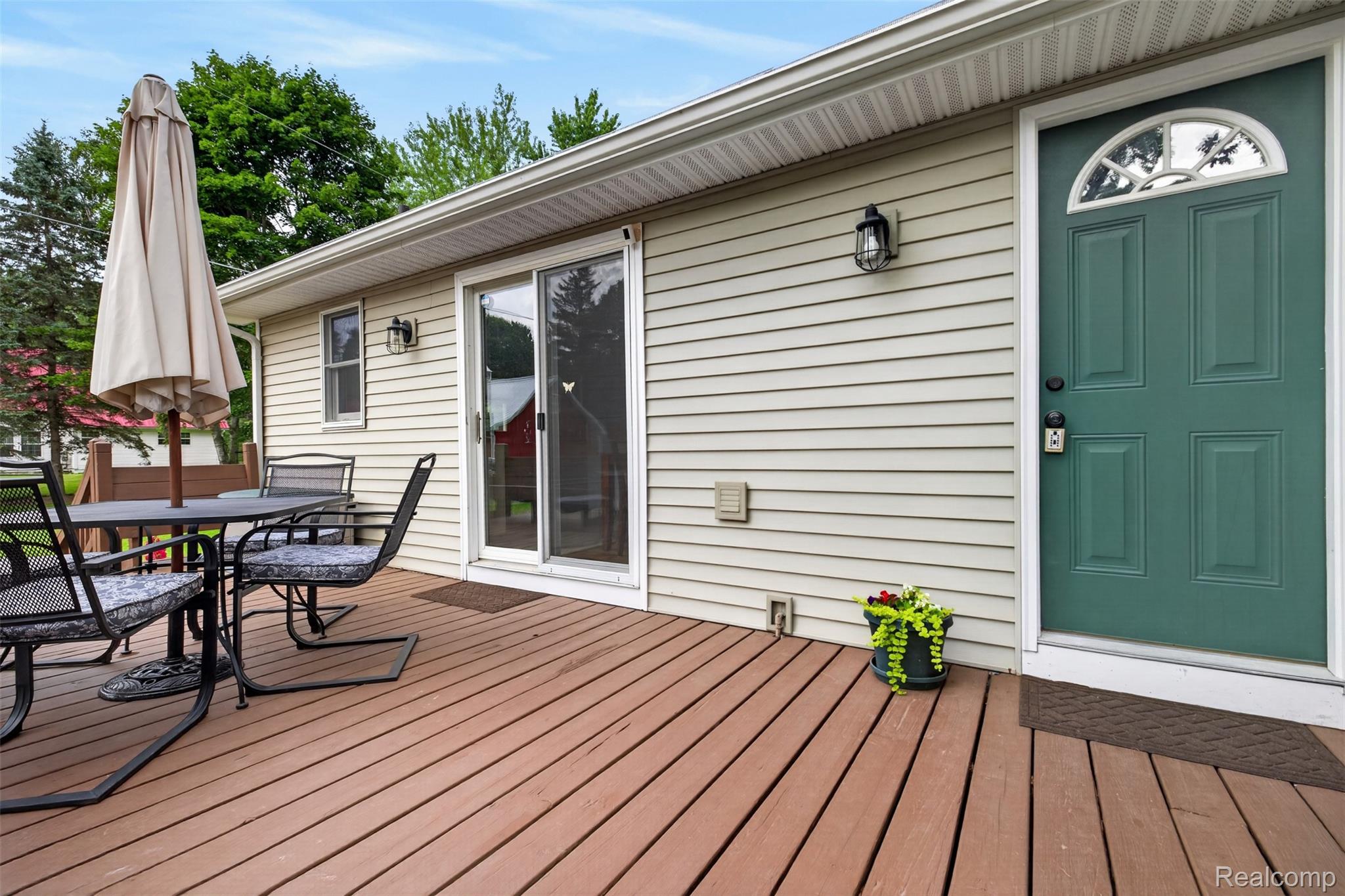 5977 Anglers Road Ortonville, MI 48462 - Photo 59 of 63 Expansive exterior deck featuring a vibrant green entry door with an arched transom window