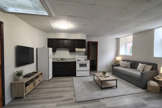 a living room with stainless steel appliances furniture and a flat screen tv