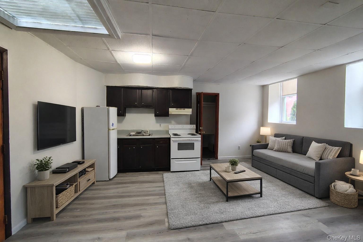 a living room with stainless steel appliances furniture and a flat screen tv