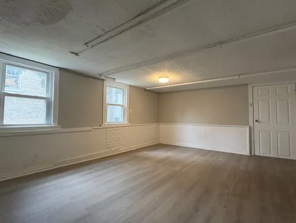 an empty room with wooden floor and windows