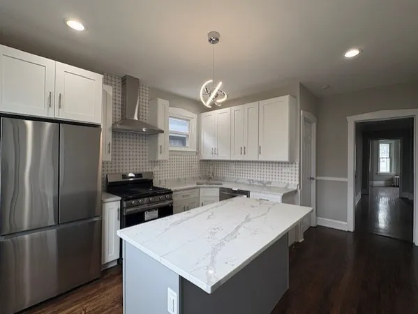 a kitchen that has a refrigerator a stove and white cabinets with wooden floor