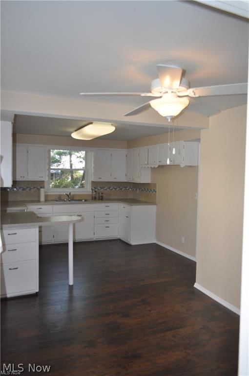 11805 Granger Road Cleveland, OH 44125 - Photo 6 of 9 Kitchen featuring dark hardwood / wood-style floors, tasteful backsplash, and white cabinetry