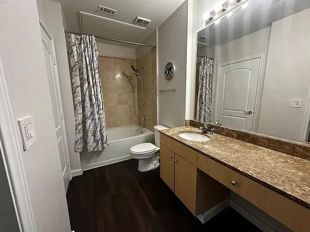 a bathroom with a granite countertop sink toilet a mirror and shower