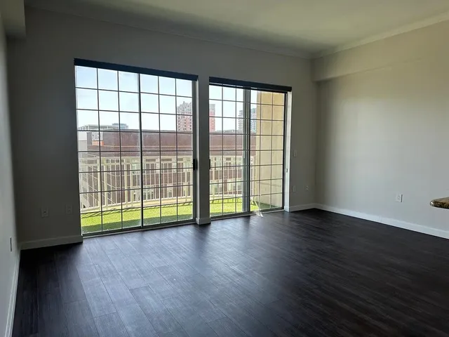 a view of an empty room with wooden floor and a window