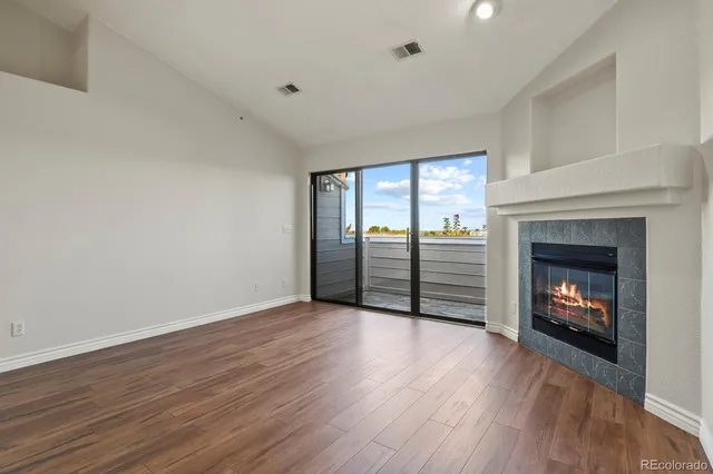 an empty room with wooden floor fireplace and windows