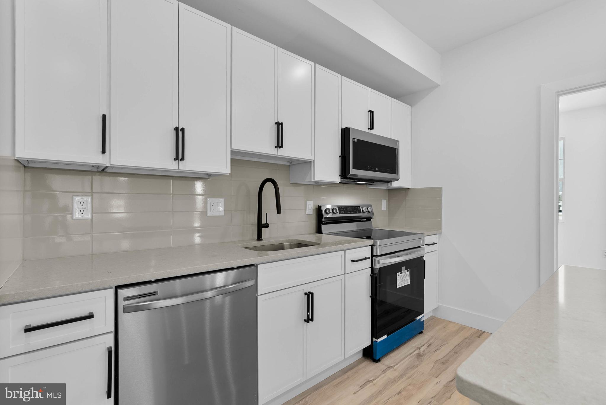 809 Diamond Street, Unit A101 Philadelphia, PA 19122 - Photo 6 of 17 a kitchen with stainless steel appliances granite countertop a stove a sink and a microwave