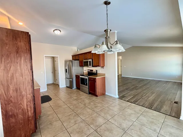 a view of a kitchen with stainless steel appliances granite countertop a stove and a refrigerator