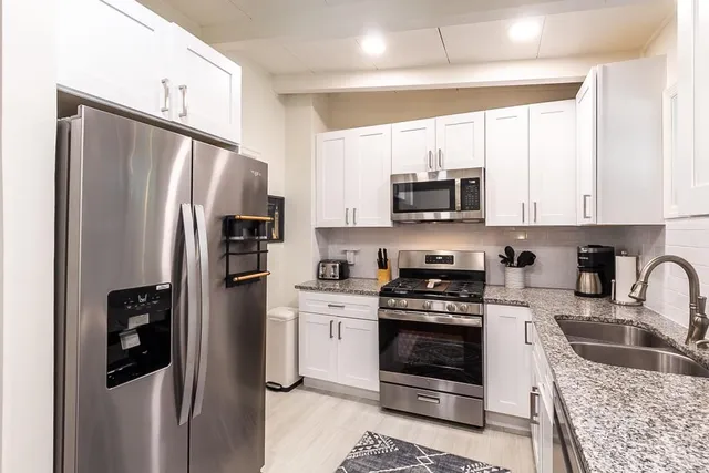 a kitchen with stainless steel appliances granite countertop a sink stove microwave and refrigerator