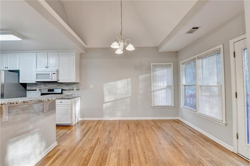 655 Golden Meadows Lane Suwanee, GA 30024 - Photo 17 of 73 a kitchen with granite countertop a stove a sink and white cabinets with wooden floor