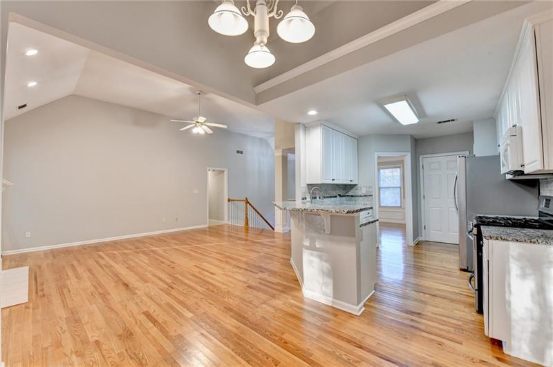 655 Golden Meadows Lane Suwanee, GA 30024 - Photo 20 of 73 a large kitchen with kitchen island a stove a sink dishwasher and white cabinets with wooden floor