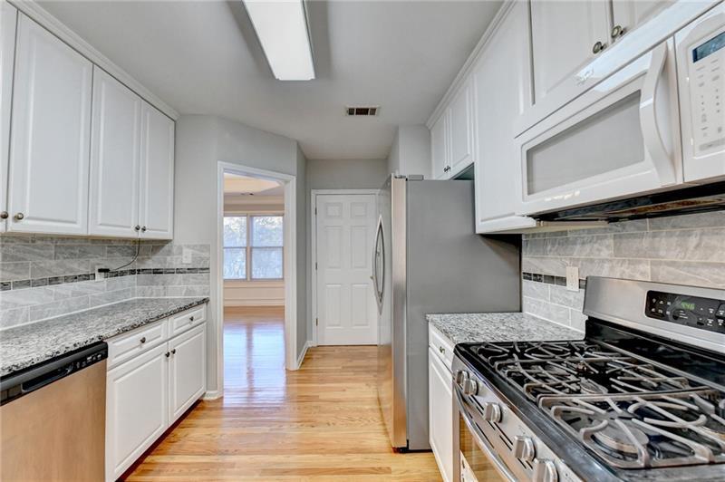655 Golden Meadows Lane Suwanee, GA 30024 - Photo 22 of 73 a kitchen with stainless steel appliances granite countertop a stove and a white cabinets