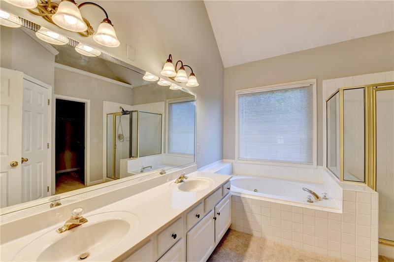 655 Golden Meadows Lane Suwanee, GA 30024 - Photo 34 of 73 a bathroom with a tub a double vanity sink and a mirror