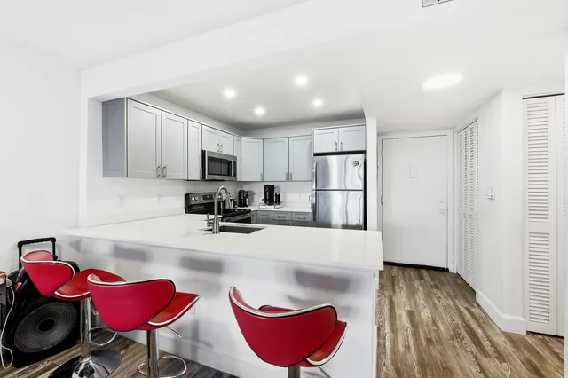 a kitchen with stainless steel appliances granite countertop a refrigerator a sink dishwasher and white cabinets with wooden floor