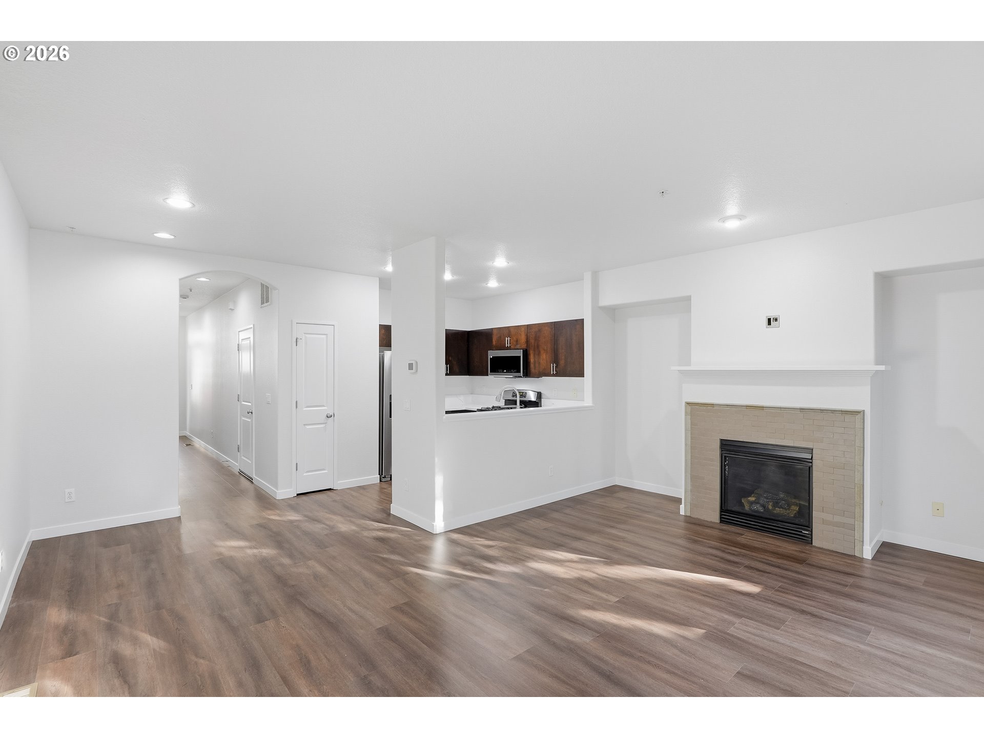 16012 Northwest Centine Lane Portland, OR 97229 - Photo 6 of 24 a view of an empty room with wooden floor and a kitchen
