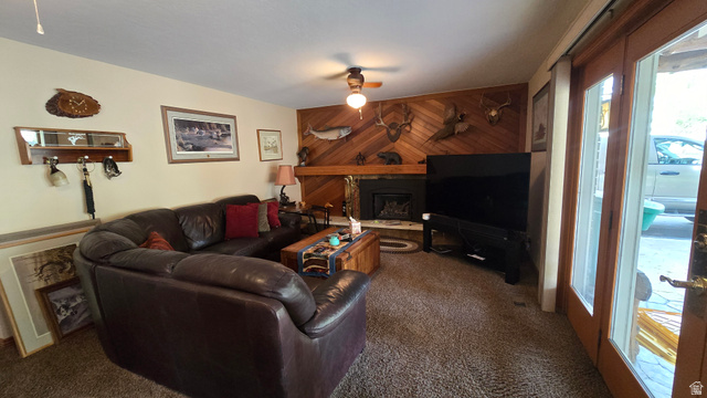 11077 Susan Drive Sandy, UT 84092 - Photo 14 of 20 Living area with an accent wall, wood walls, a fireplace, carpet floors, and ceiling fan