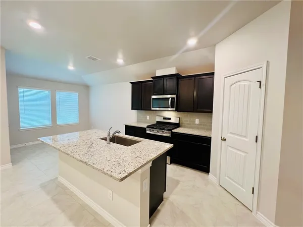 a kitchen with a sink refrigerator and microwave