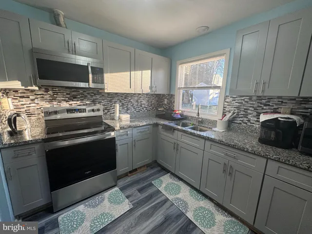 a kitchen with stainless steel appliances granite countertop a sink stove and microwave