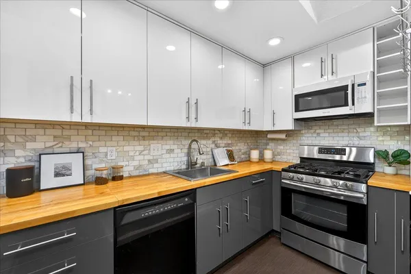 a kitchen with stainless steel appliances granite countertop a sink a stove and cabinets
