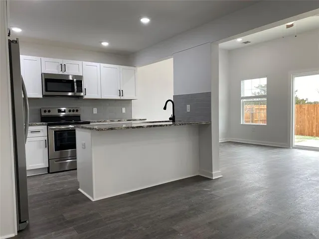 a kitchen with stainless steel appliances granite countertop a stove a sink and a microwave
