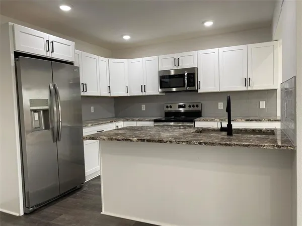 a kitchen with stainless steel appliances granite countertop a refrigerator a stove a sink a microwave and cabinets