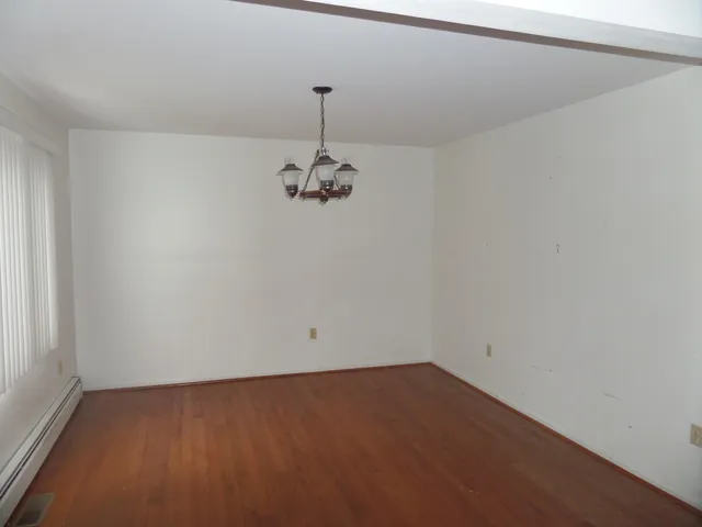 a view of a room with a hanging light and hardwood floor