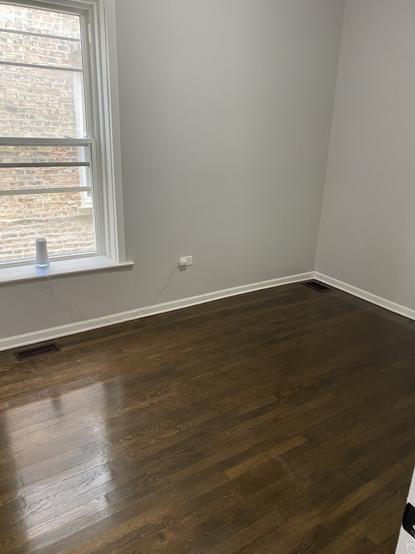 7425 South Princeton Avenue, Unit 1 Chicago, IL 60621 - Photo 7 of 24 a view of an empty room with wooden floor and a window
