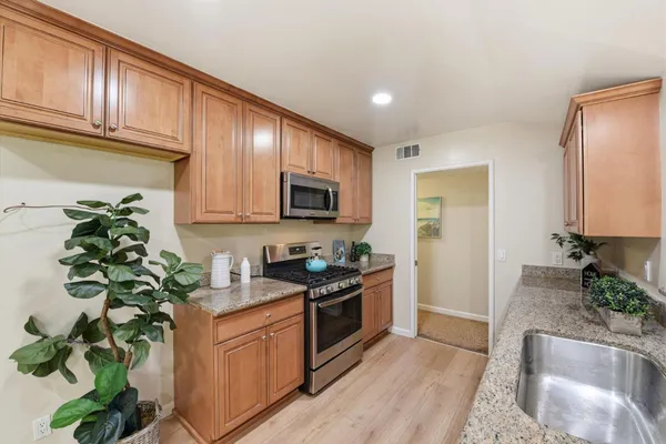 a kitchen with stainless steel appliances granite countertop a stove a sink a refrigerator a microwave oven and a refrigerator