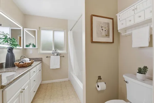 a bathroom with a granite countertop sink mirror vanity and toilet